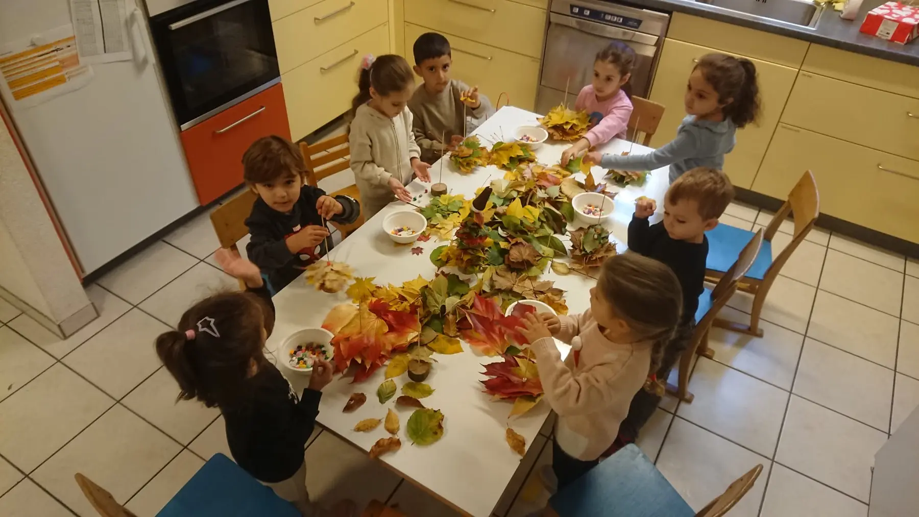 Kinder gestalten gemeinsam mit farbigen Herbstblättern