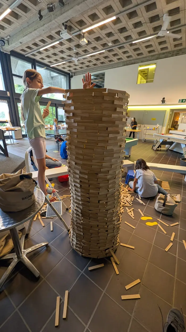 Kinder bauen gemeinsam einen grossen Turm aus Holzplättchen